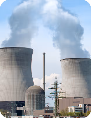 Nuclear power plant with two large cooling towers emitting steam against a blue sky.